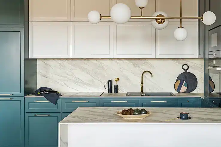 Mezclar estilos sin equivocarse: el secreto está en el equilibrio Cocina moderna con isla de mármol y muebles en tonos azul petróleo.