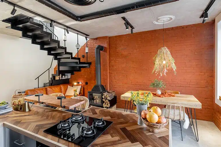 Las casas con personalidad no siguen las tendencias: siguen a quienes viven en ellas Salón de estilo industrial con pared de ladrillo, madera y mobiliario de diseño